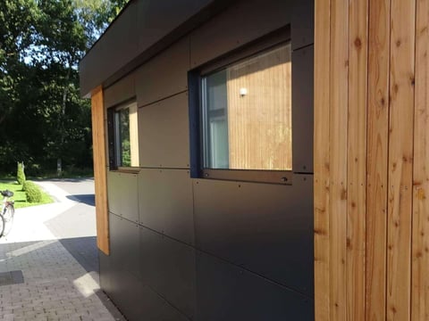 HPL Schichtstoffplatten an einer Gebäudefassade kombiniert mit Holzelementen und Fenstern