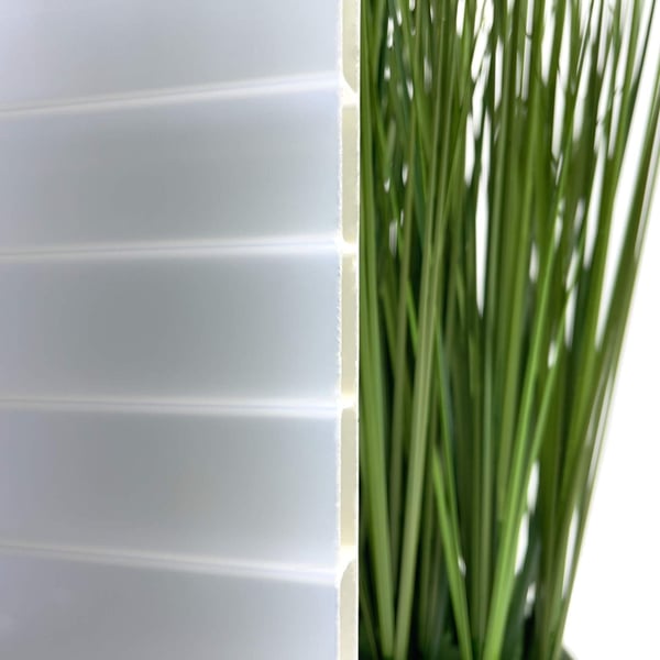 Detailansicht der 16 mm Acrylglas Stegdoppelplatte gold-opal mit Pflanzen im Hintergrund