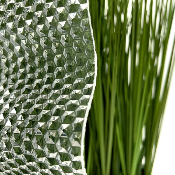 Detailaufnahme der Acrylglas Wellplatte 76/18 klar, 3,00 mm, mit Wabenstruktur, daneben gruene Pflanzen