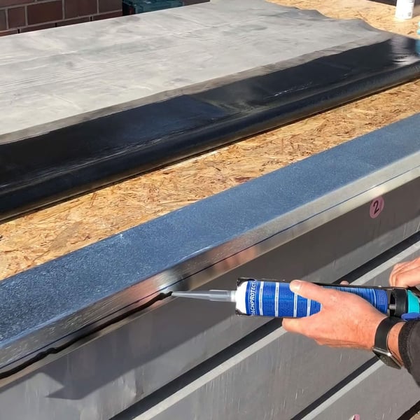 Montage des schwarzen Anschlussklebers Flex auf einem Dachblech mit einer Kartuschenpistole