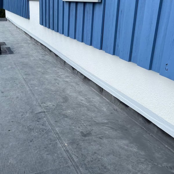 Graues Dach Reparaturband an einer weissen Wand auf einem Flachdach, blaue Holzverkleidung