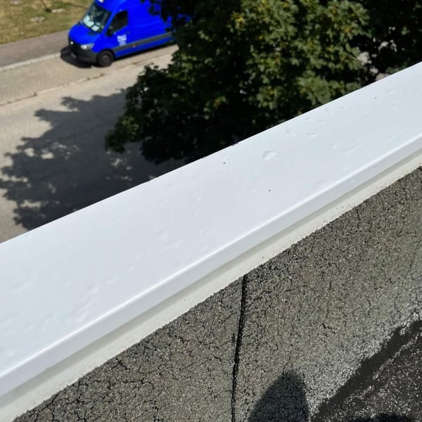 Graues Dach Reparaturband auf einer Dachkante, Blick auf eine Strasse mit blauem Lieferwagen