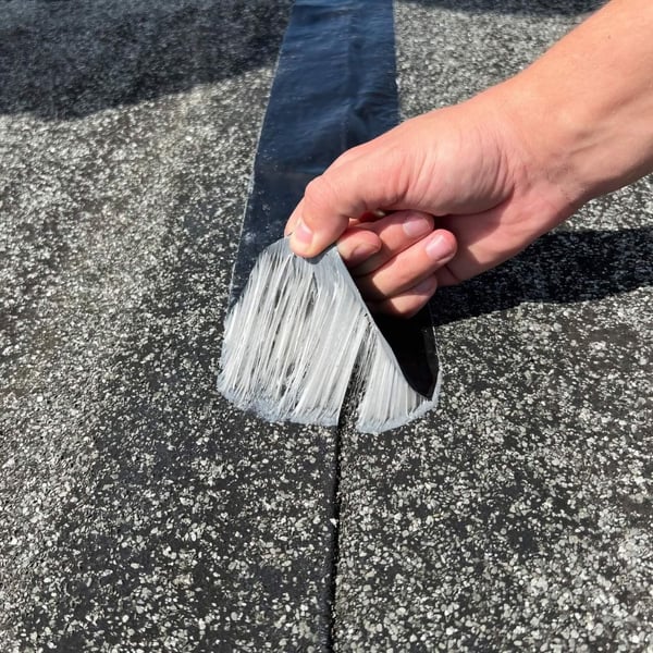 DACHPROTECT Dach Reparaturband EPDM schwarz wird von Hand abgezogen