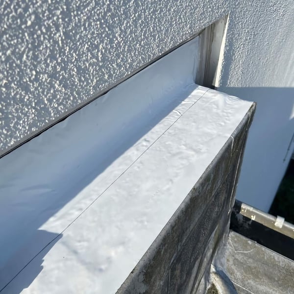 Graues Dach Reparaturband an der Kante eines Flachdaches, um eine Ecke gelegt