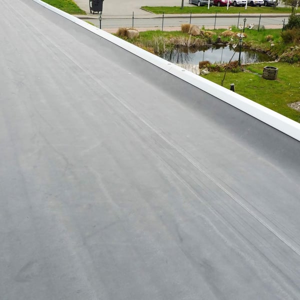 Verlegte schwarze EPDM Dachfolie auf einem Flachdach mit weißer Attika, Blick über das Dach
