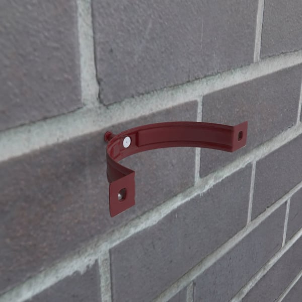 Kirschrote Fallrohrschelle aus Stahl, Polyurethan beschichtet, an einer Ziegelwand montiert