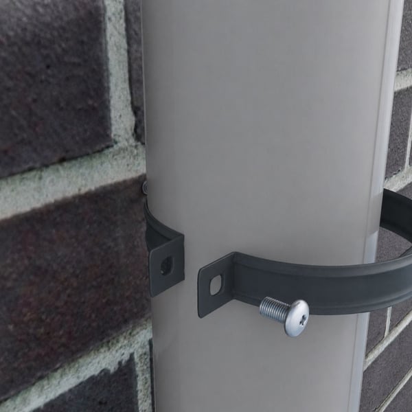 Fallrohrschelle aus anthrazitgrauem Stahl um ein helles Fallrohr an Ziegelwand
