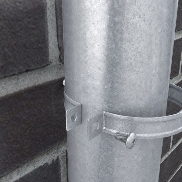 Detailansicht der verzinkten Fallrohrschelle, die ein Fallrohr an einer Ziegelwand befestigt