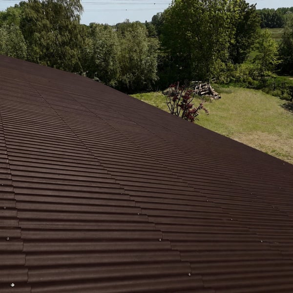 Grossflächiges Dach aus dunkelbraunen Faserzement Wellplatten Europa Profil 5 auf einem landwirtschaftlichen Gebäude