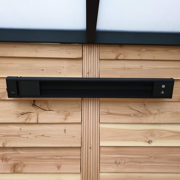 Schwarze Aluminium-Heizung an einer vertäfelten Holzwand, mittig montiert