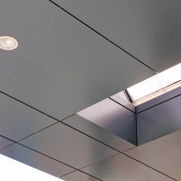 Deckenverkleidung mit quadratischen Platten und integrierten Leuchten, eine Öffnung für Tageslicht