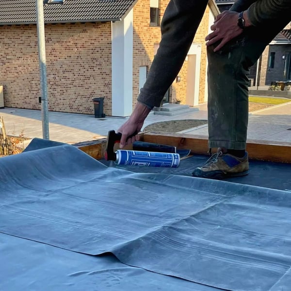 Person sprüht mit Komfort-Sprühdosen-Handgriff auf Dachabdichtung, blaue Sprühdose sichtbar