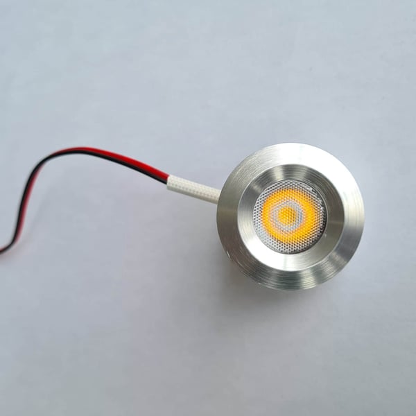 Detailansicht eines blanken LED Extra Spots aus Aluminium mit gelb leuchtendem Licht