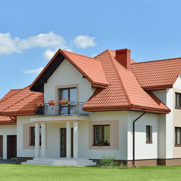 Ziegelrotes Pfannenblech Szafir 350/15 auf einem Wohnhaus mit Balkon