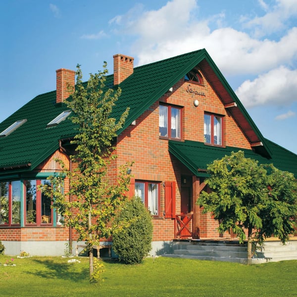 Ziegelhaus mit moosgrünem Pfannenblech Szafir 350/15 Dach und roten Fensterrahmen