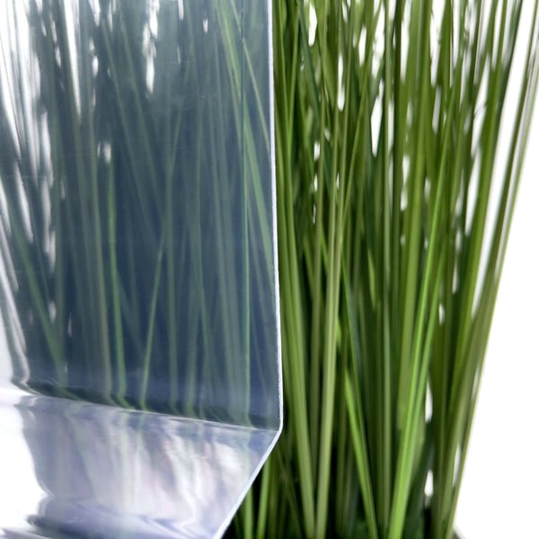 PVC Spundwandplatte klarbläulich, 1,50 mm, Detailansicht der transparenten Oberfläche vor Pflanzenhintergrund