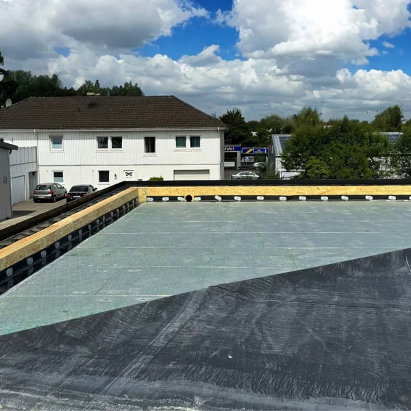 Dachansicht mit verlegtem schwarzen EPDM Randfixierstreifen an der Attika