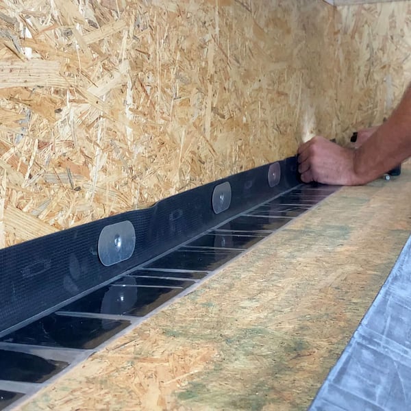 Montage des schwarzen EPDM Randfixierstreifens mit Befestigungselementen an einer Holzattika