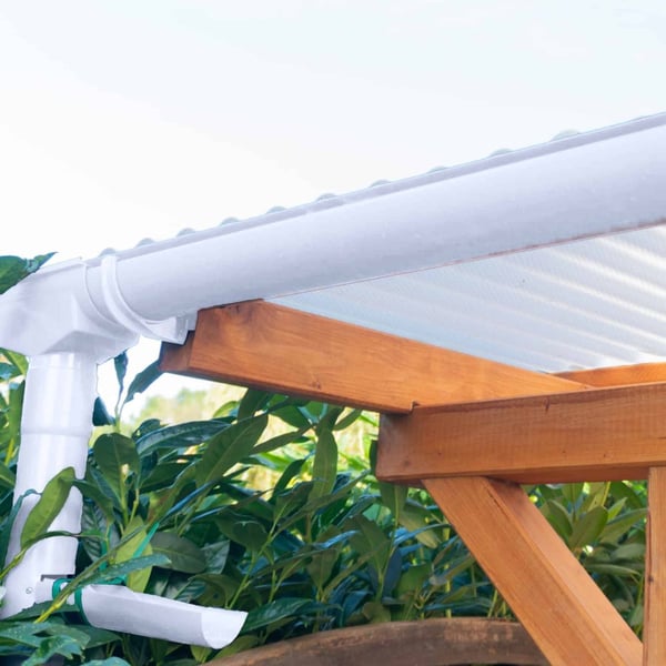 Regenwasserfänger PVC weiß, montiert an einer Dachrinne mit Regenfallrohr und Holzkonstruktion
