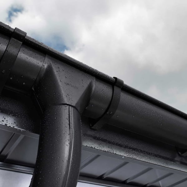 Tiefschwarzer Rinnenablauf und Dachrinne von Niagara mit Wassertropfen bei bewolktem Himmel