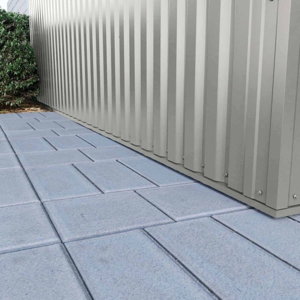 Sockelleiste Aluminium Graualuminium am unteren Abschluss einer Profilblechwand, auf Pflastersteinen