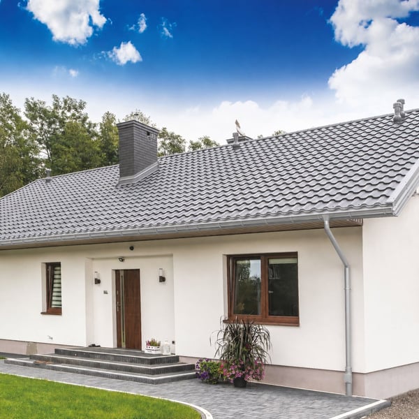 Haus mit montierter Stahl Dachrinne in Weißaluminium, Fallrohr und Gartenanlage als Anwendungsbeispiel