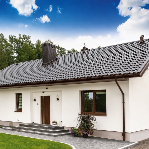 Weisses Haus mit Niagara Stahl Dachrinnen-System in Schokoladenbraun, komplett am Dach verbaut