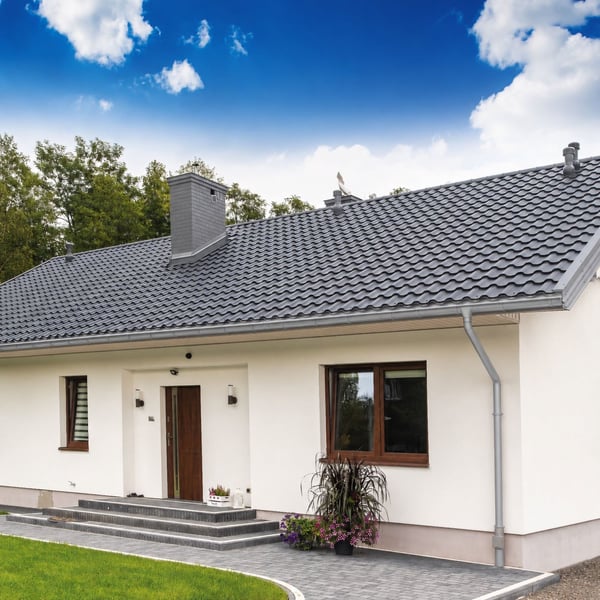 Weisses Haus mit dunklem Dach und montierter Stahl Dachrinne in Graualuminium, gesamtes Anwendungsbeispiel