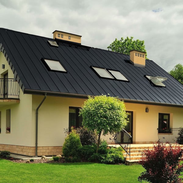 Anthrazitgraues Stehfalzblech PD-510-S auf einem Wohnhaus mit Dachfenstern und Garten