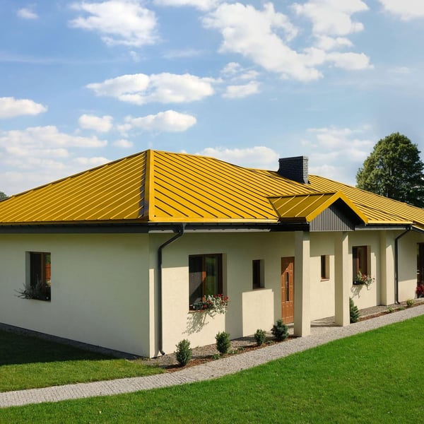 Einfamilienhaus mit rapsgelbem Stehfalzdach und schwarzer Dachrinne, Seitenansicht