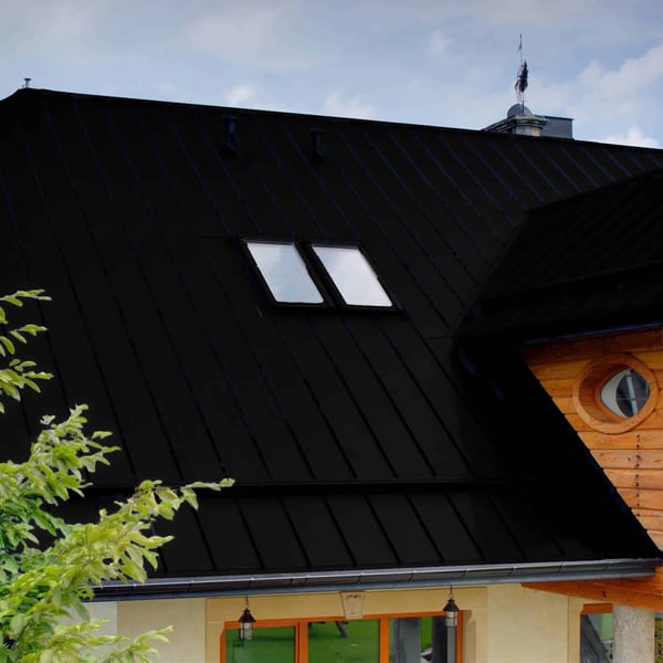 Stehfalzblech PD-510-S Tiefschwarz auf dem Dach eines Einfamilienhauses, Nahaufnahme mit zwei Dachfenstern