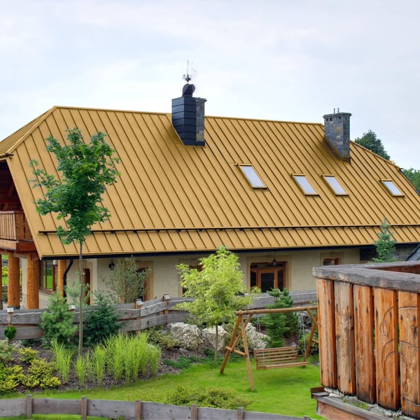 Stehfalzblech PD-510-S Mikro Sandgelb auf einem grossen Wohnhaus mit mehreren Dachfenstern