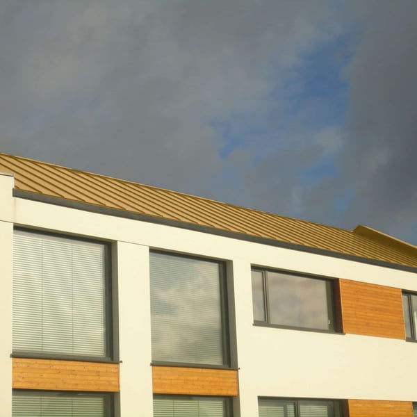 Stehfalzblech PD-510-S Mikro Sandgelb auf einem modernen Gebaeude mit grossen Fenstern