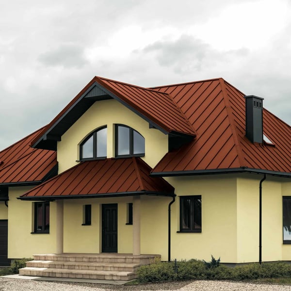 Haus mit Dach aus Stehfalzblech PD-510-S Mikro Ziegelrot, Vorderansicht mit Gaube