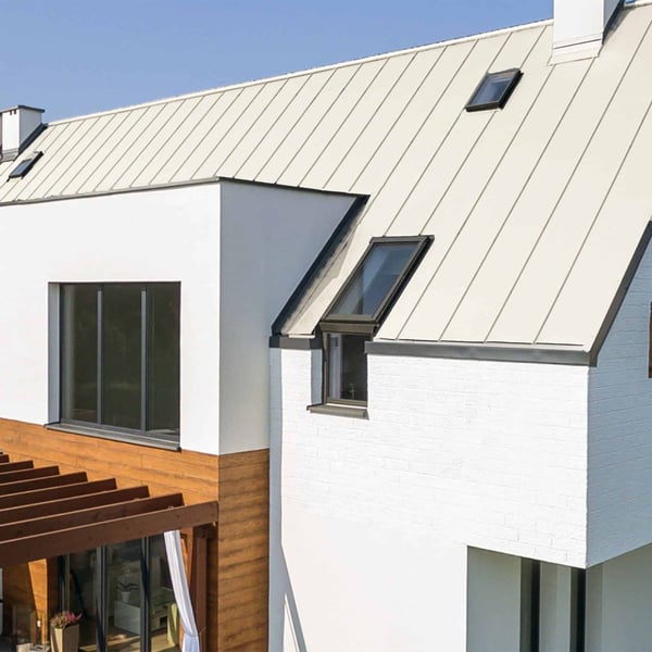 Stehfalzblech PD-510-S Mikro in Reinweiß auf einem modernen Haus mit Flachdach-Anbau und Dachfenstern
