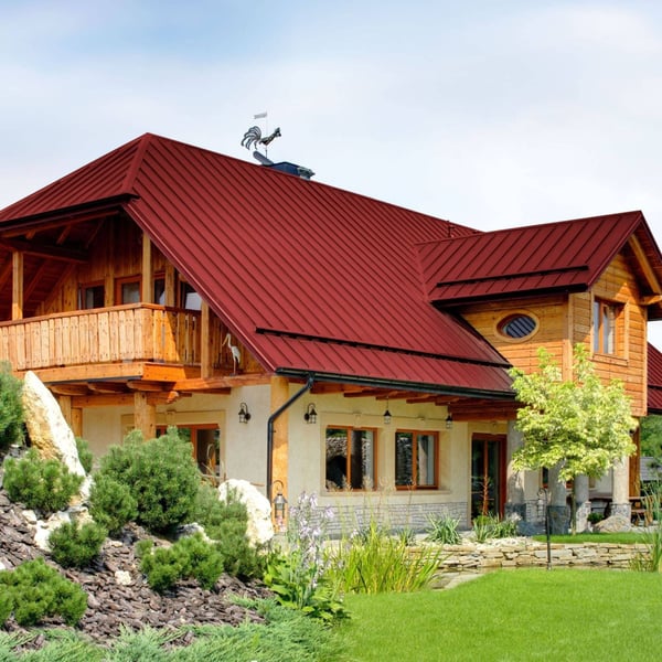 Stehfalzblech PD-510-S Kirschrot auf einem Wohnhaus mit Holzbalkon und Wetterhahn