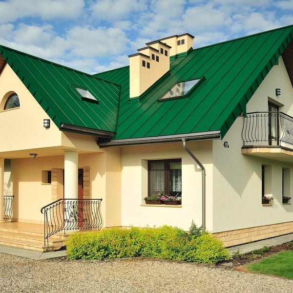 Minzgrünes Stehfalzdach auf einem Einfamilienhaus mit Gauben und Dachfenstern, sonniger Tag