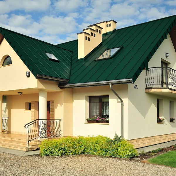 Stehfalzblech PD-510-S Nano in Grün auf einem Wohnhaus mit Dachfenstern und Schornsteinen, Verlegung am Dach
