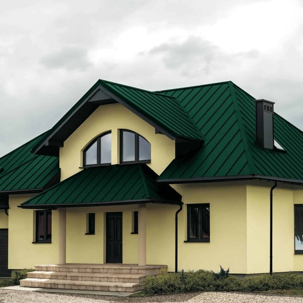 Stehfalzblech PD-510-S Nano in Grün auf einem Wohnhaus mit Gauben und Schornstein, Verlegung am Dach