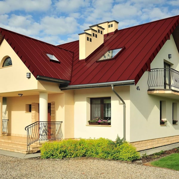 Stehfalzblech PD-510-S Kirschrot auf einem Wohnhaus mit Gauben und Schornsteinen, Verlegung