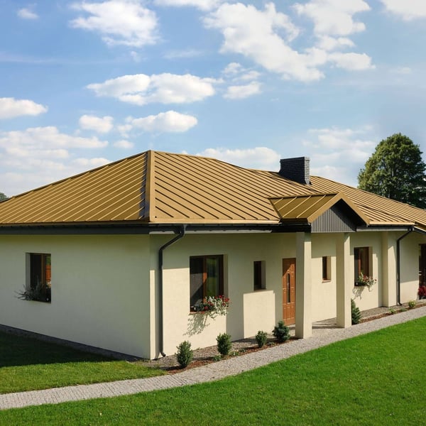 Stehfalzblech PD-510-S Sandgelb auf einem Bungalow mit dunklen Dachrinnen und Fenstern
