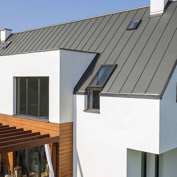 Stehfalzblech PD-510-S Graualuminium auf einem Hausdach mit Dachfenstern und weisser Fassade