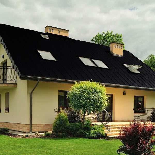 Stehfalzblech PD-510-S Trapez Tiefschwarz auf einem Wohnhaus mit Dachfenstern und Garten