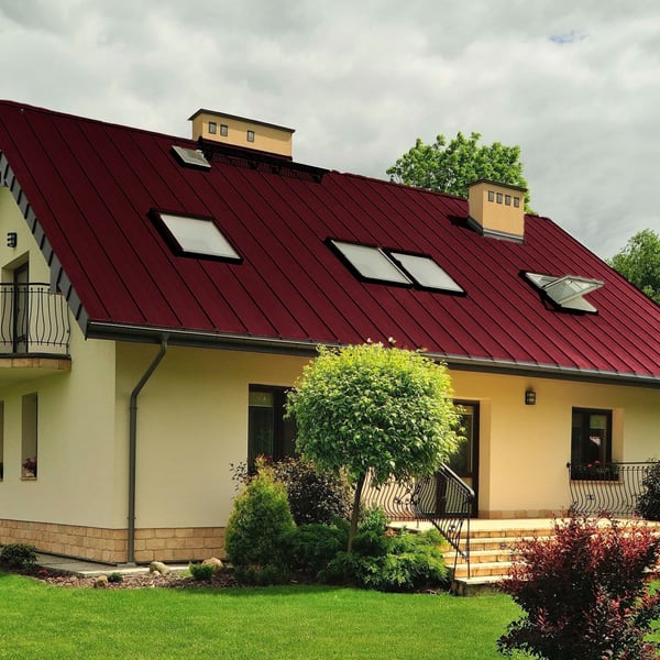 Stehfalzblech PD-510-S weinrot auf einem Wohnhaus mit Dachfenstern und Garten