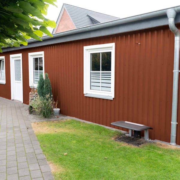 Seitenansicht eines Gebäudes mit Trapezblech 20/1100 Wand in Kupferbraun RAL 8004, Anwendungsbeispiel