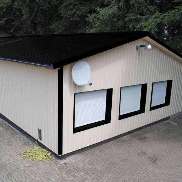 Trapezblech 35/207 Tiefschwarz auf dem Dach einer hellen Lagerhalle mit Satellitenschüssel