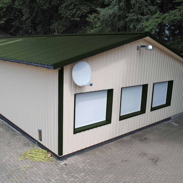 Trapezblech 35/207 Chromoxidgrün auf einem beigefarbenen Gebäude mit Satellitenschüssel und Fenstern