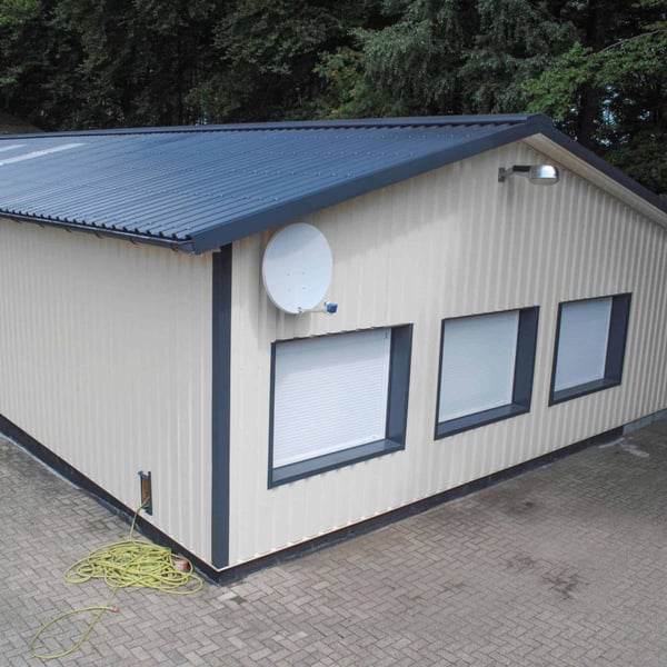 Trapezblech 35/207 Wand, Lichtgrau RAL 7035, an einer kleinen Halle mit dunklem Dach