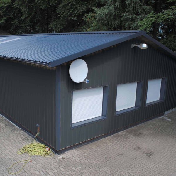 Trapezblech 35/207 Wand, anthrazitgrau, an der Fassade eines Gebaeudes mit Fenstern und Satellitenschuessel