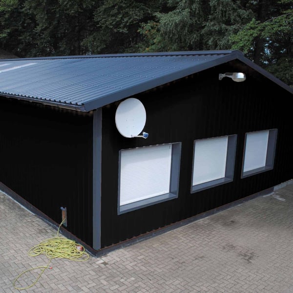 Trapezblech 35/207 Tiefschwarz als Wandverkleidung einer Halle mit Fenstern und Satellitenschuessel